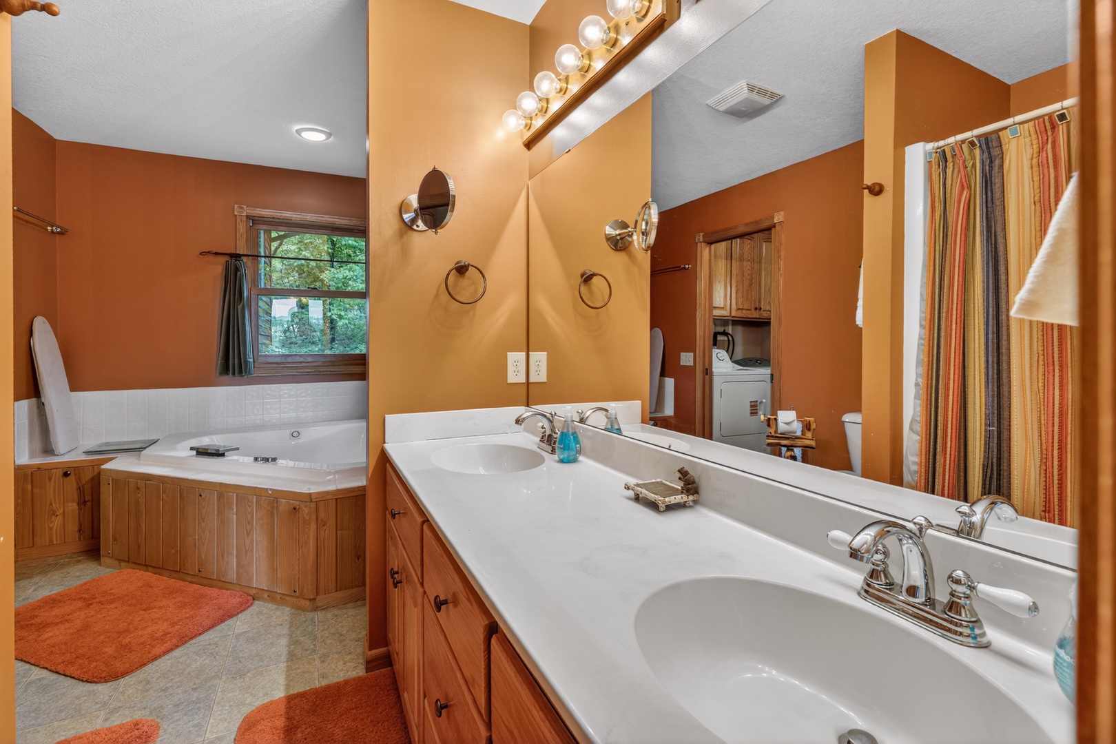 Unwind in your spa-like bathroom featuring a large soaking tub, dual vanities, and warm natural light—your perfect retreat after exploring the area.