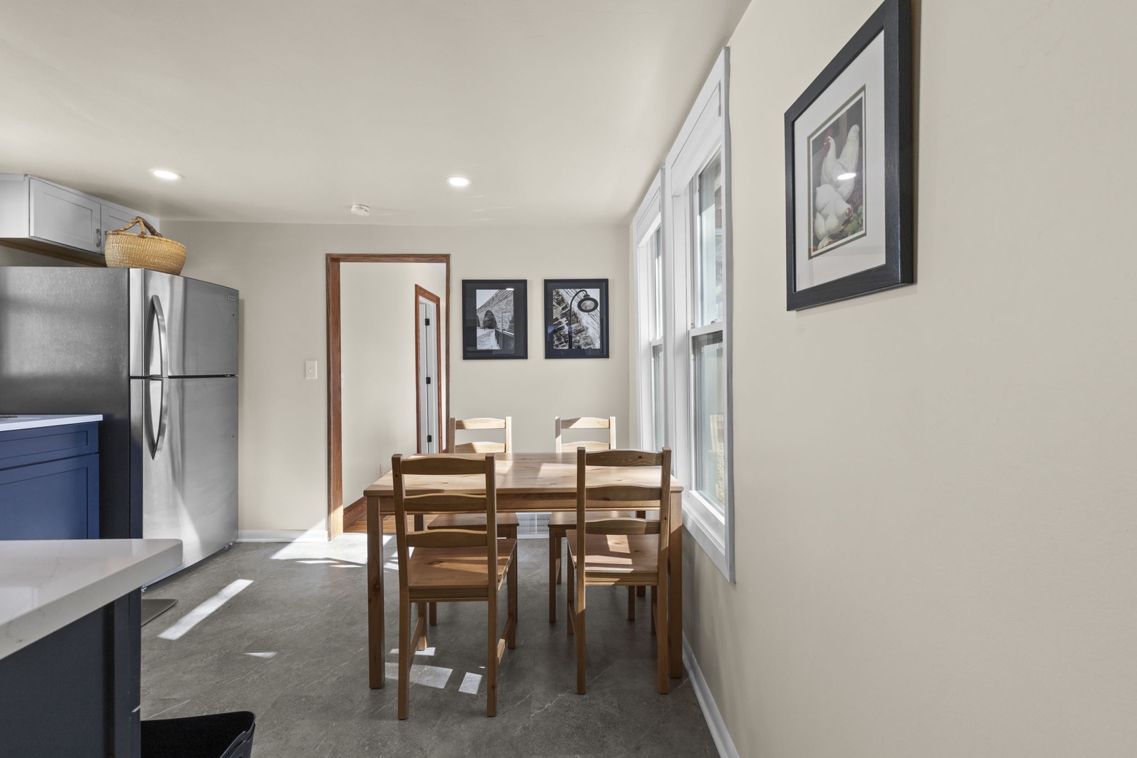 Eat-in kitchen dining area with natural wood table, seating for four, and large windows overlooking the backyard — casual dining at its best.