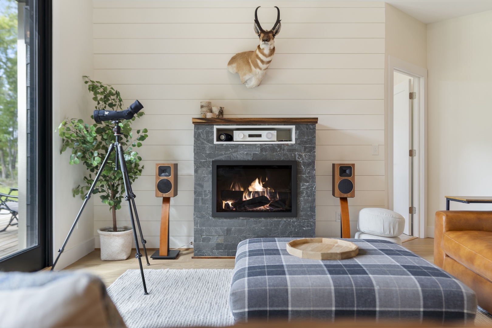 Unwind in this inviting living room where the stone fireplace radiates warmth and the telescope invites stargazing from your private deck—your perfect mountain escape awaits.