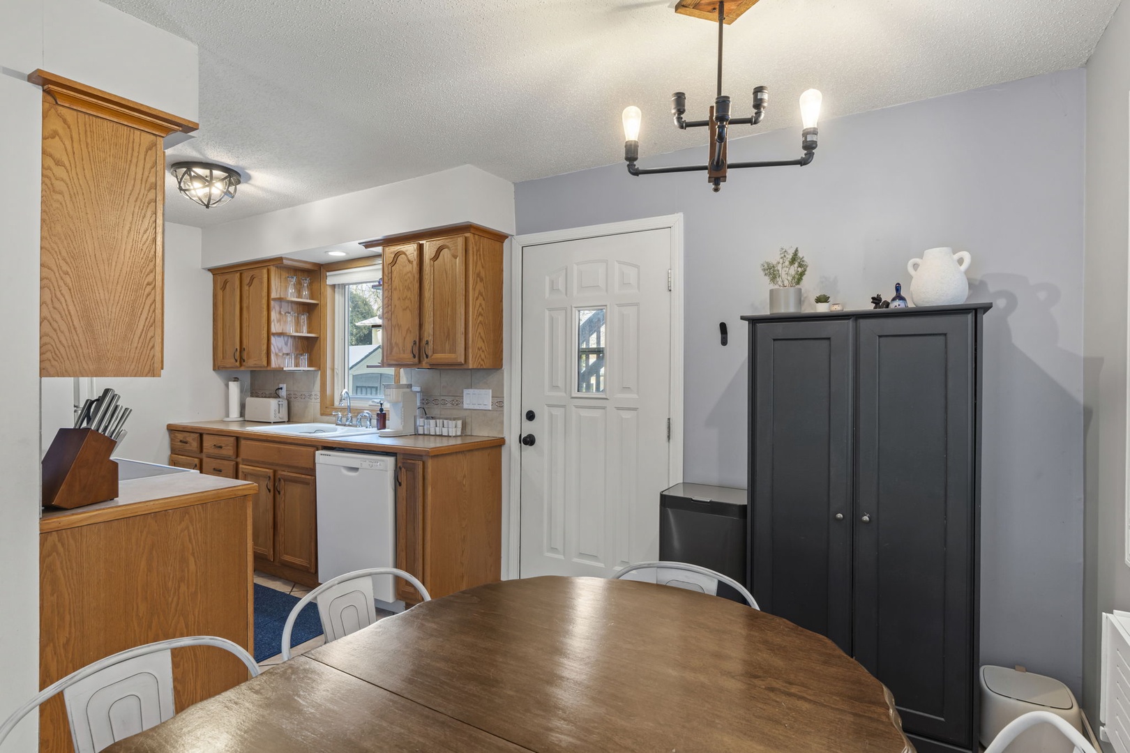 Your fully equipped kitchen flows seamlessly into the dining space, perfect for preparing meals and gathering around the warm wood table.