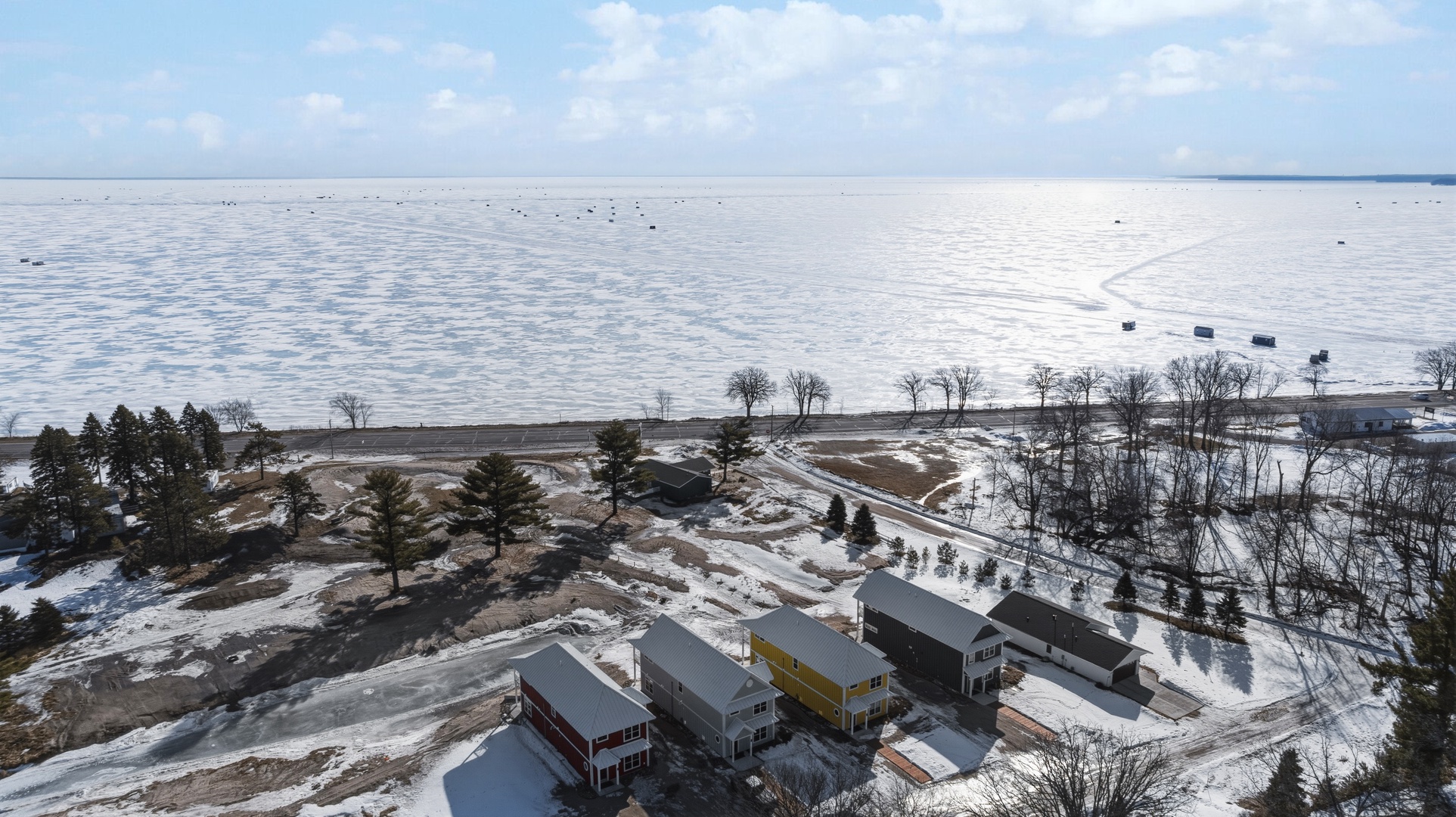 Aerial view of lakeside property with frozen lake and pine trees