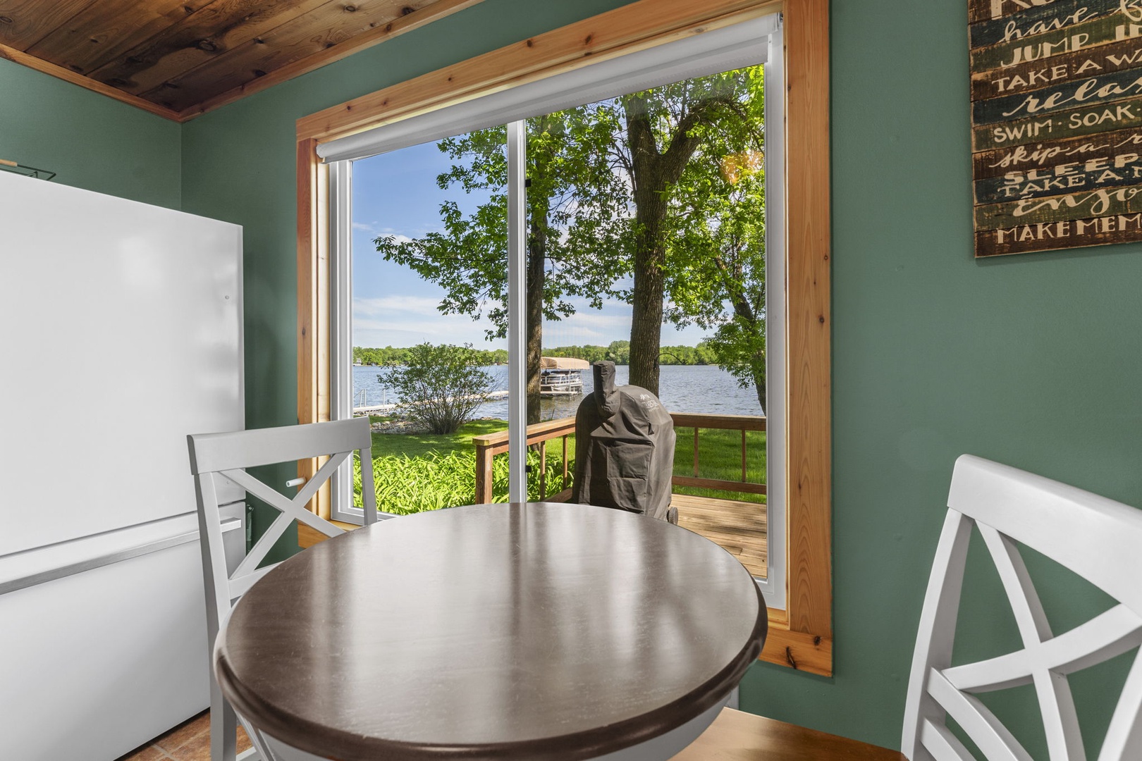 Picture yourself at this cozy dining nook with serene lake views just beyond your door. The soft green walls and rustic wood accents create a warm retreat where morning coffee tastes even better.