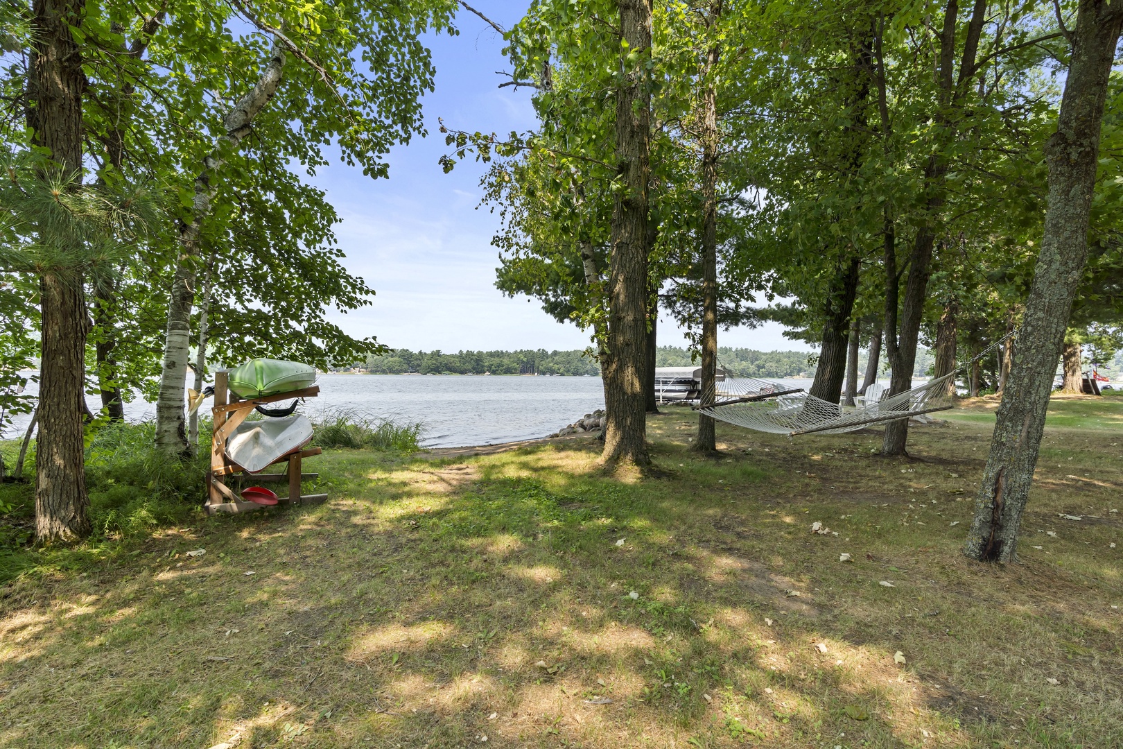 A lakefront property featuring a peaceful shoreline surrounded by mature trees and natural landscape, with a dock extending into the water for easy access.