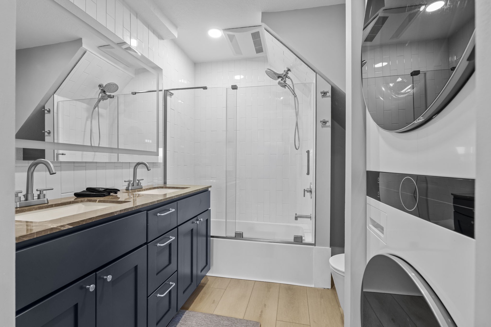 Your sleek bathroom features dual vanities, a luxurious glass-enclosed tub-shower combo, and convenient in-unit laundry—everything you need for comfort.