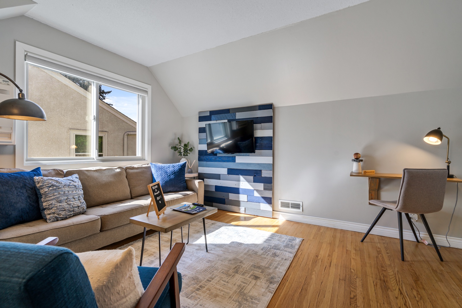 15 — Sunlit Upper Living Room with Feature Wall Smart TV and Dedicated Workspace