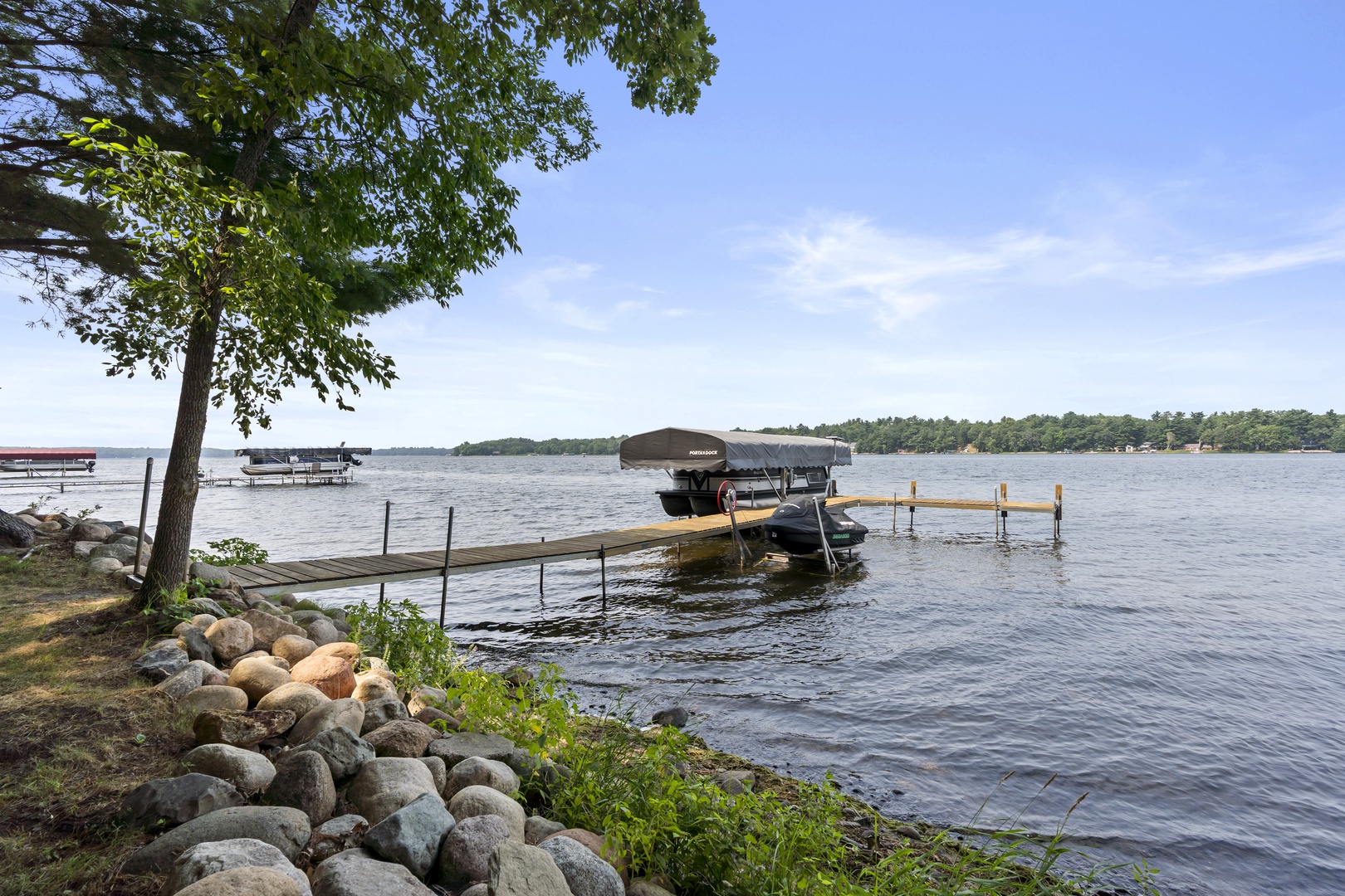 Private dock leads to sparkling lake waters framed by tree-lined shores, perfect for kayaking, boating, and waterfront relaxation.