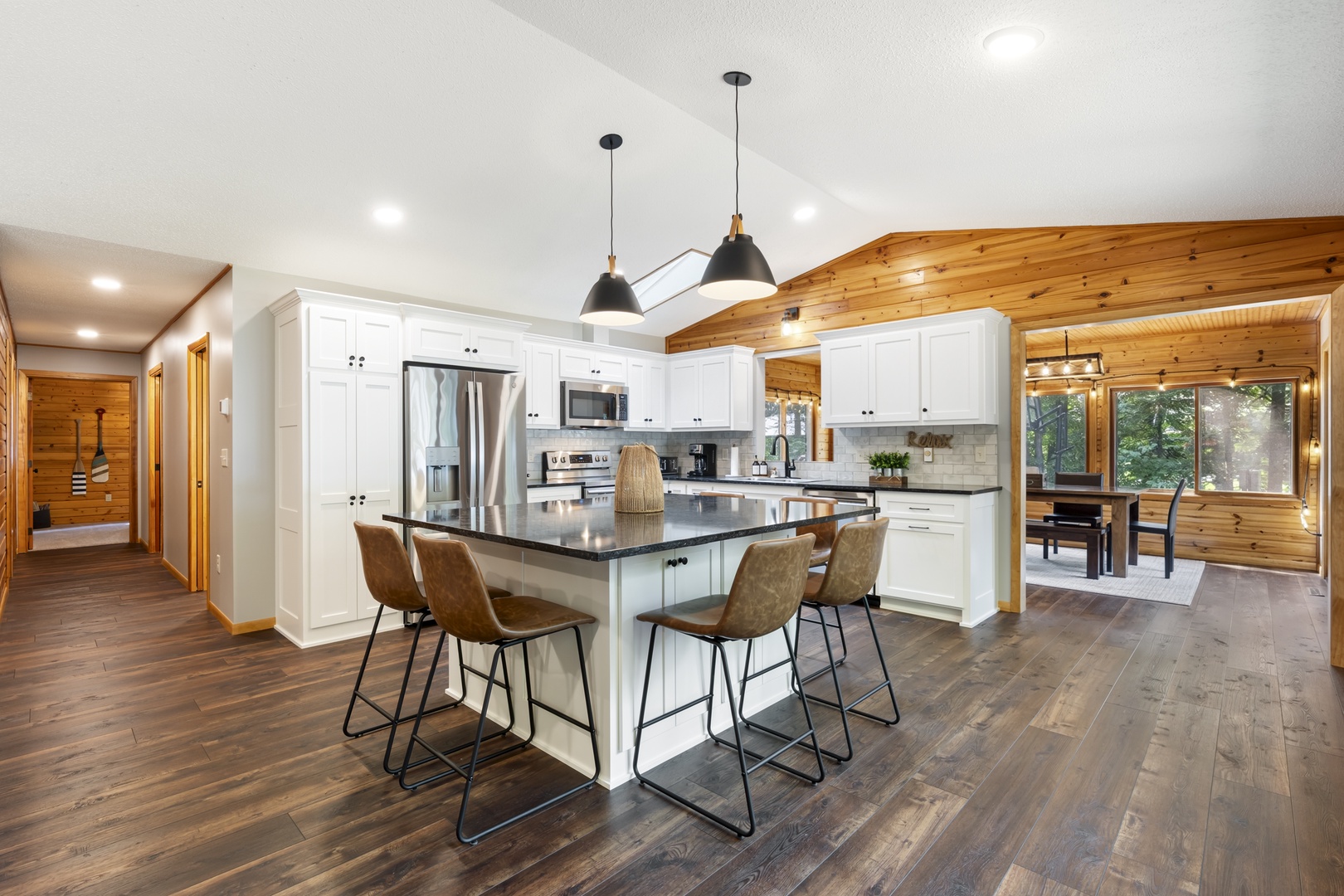 Gather around your spacious kitchen island with sleek countertops and modern pendant lighting. Crisp white cabinetry meets warm wood accents, creating the perfect spot for morning coffee or evening meals together.