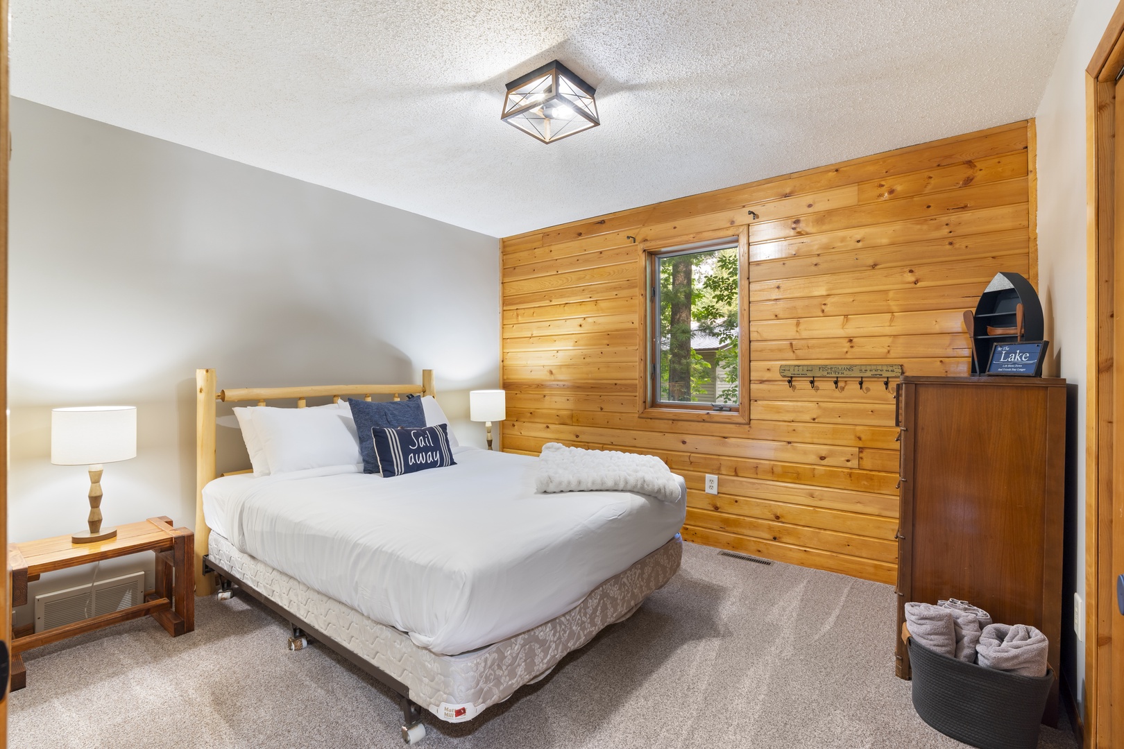 Wake to pine-paneled warmth and soft natural light filtering through your window. Cozy linens, rustic touches, and a dresser with fresh towels make you feel instantly at home.