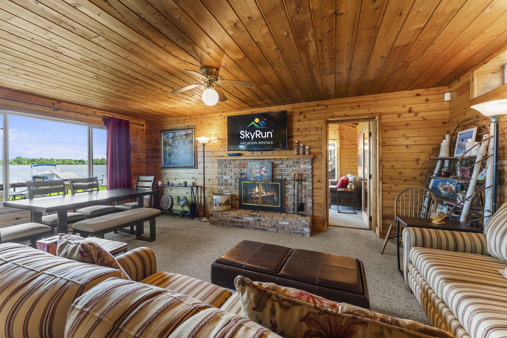 Unwind in your cozy lakeside living room with vaulted wood ceilings, a stone fireplace, and lake views framing every moment of your stay.