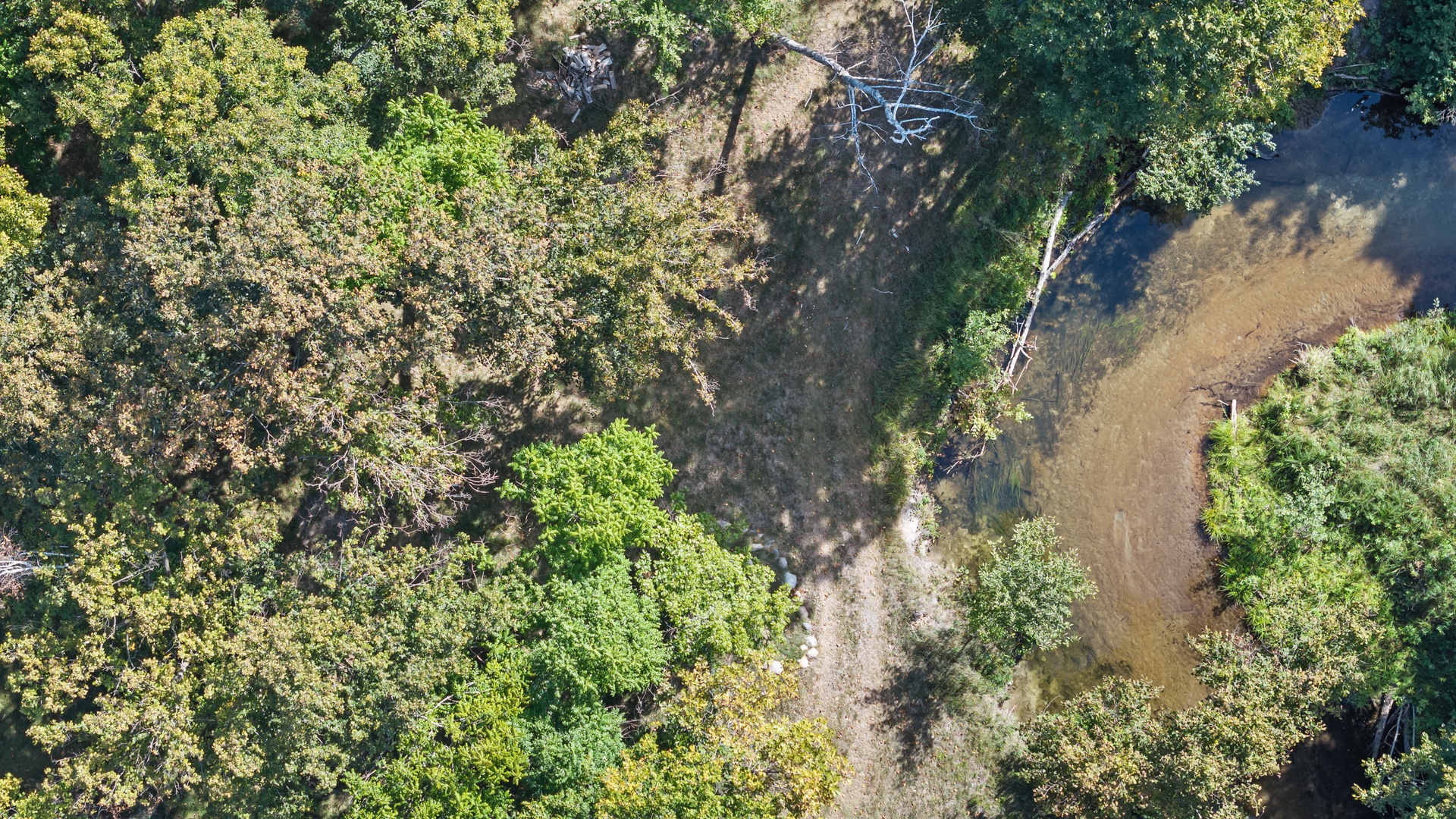 Aerial view showcasing the property's lush natural surroundings, with dense forest canopy and a tranquil waterway meandering through the landscape.