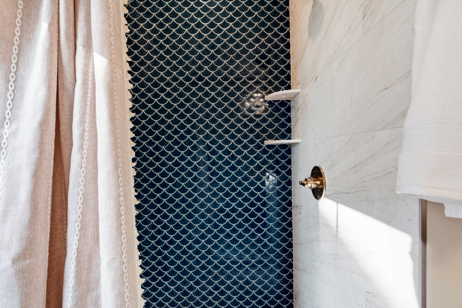 Walk-in shower with blue fish scale tile and marble walls