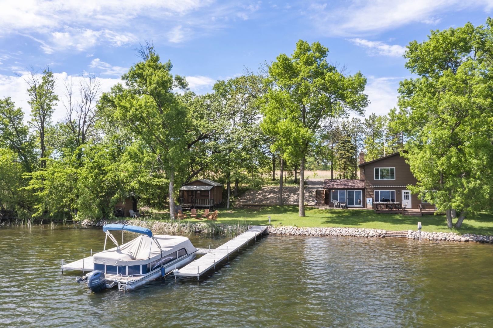 Waterfront property nestled in lush greenery with private dock. The setting offers a peaceful lakeside retreat surrounded by mature trees and natural landscaping.