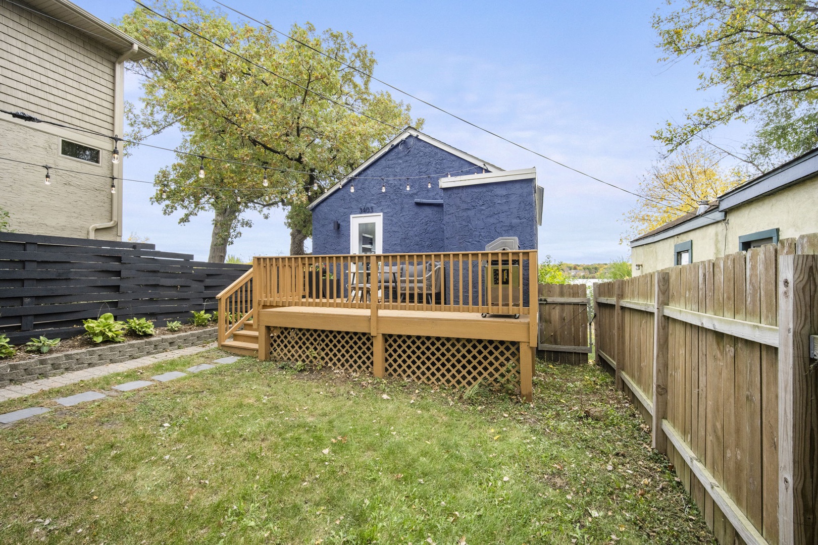 A peaceful fenced backyard with a raised wooden deck, perfect for your morning coffee or evening relaxation under the open sky.