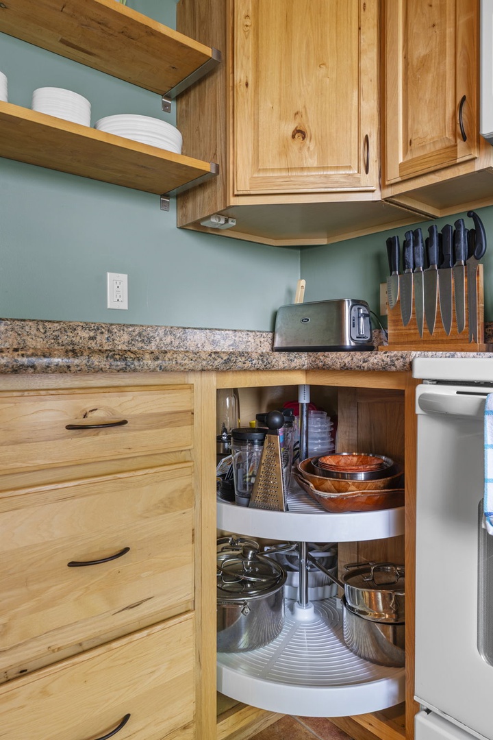 Your well-appointed kitchen features warm wood cabinetry, granite countertops, and thoughtful storage including a convenient lazy Susan for easy access to cookware and essentials.