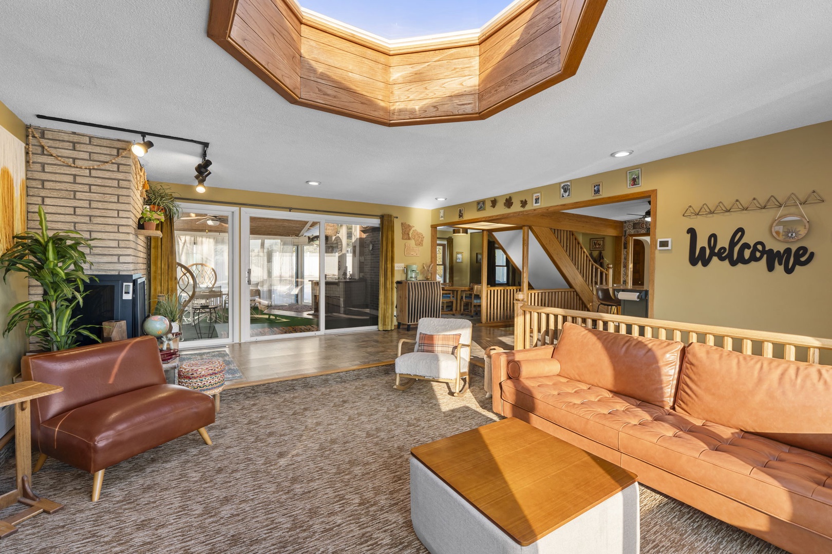 Step into your welcoming living room featuring rich leather seating, warm wood accents, and natural light streaming through the stunning skylight above.