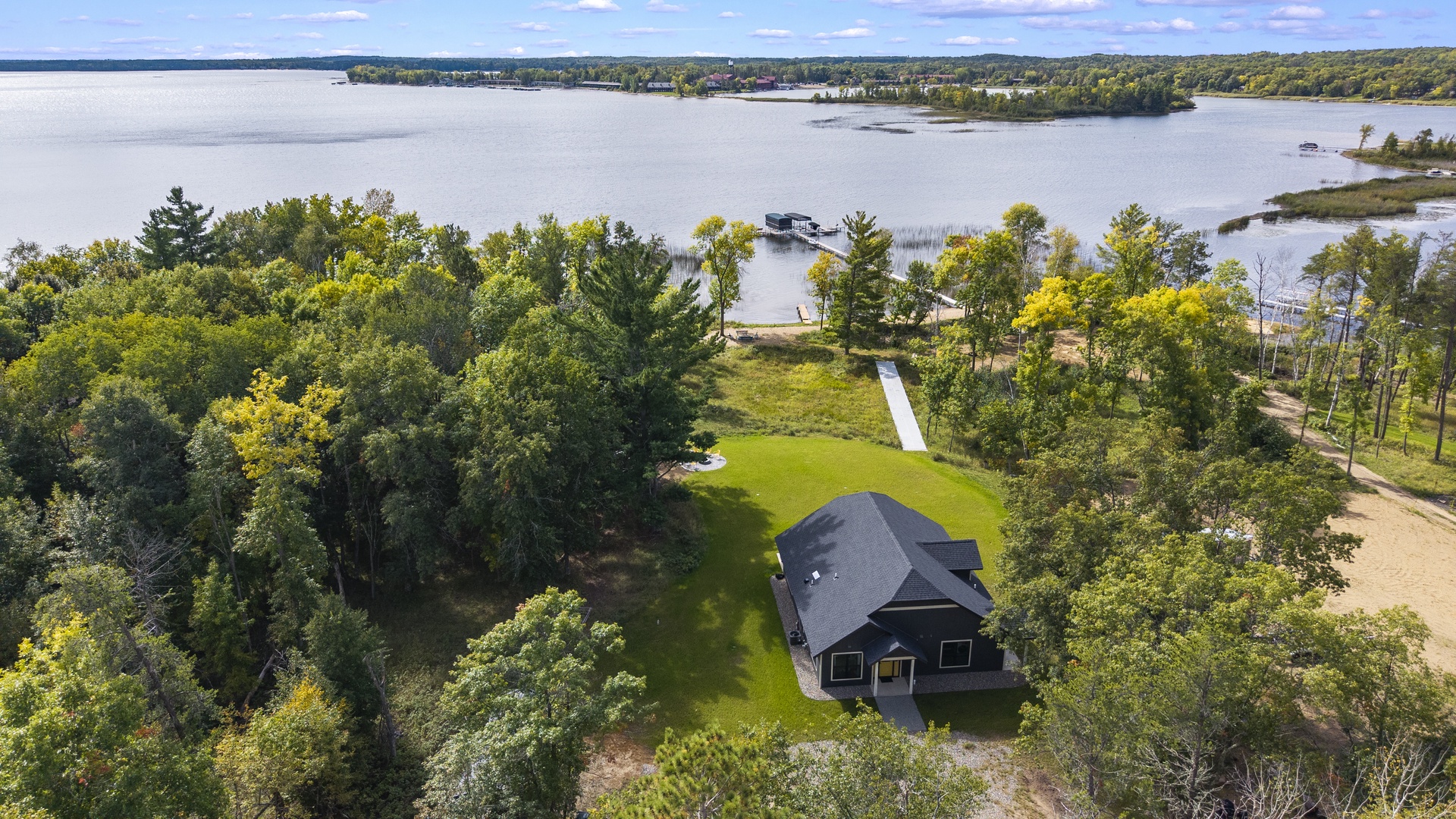 A secluded lakefront property nestled among mature trees with private water access and dock, surrounded by pristine natural landscape and peaceful island-dotted waters.