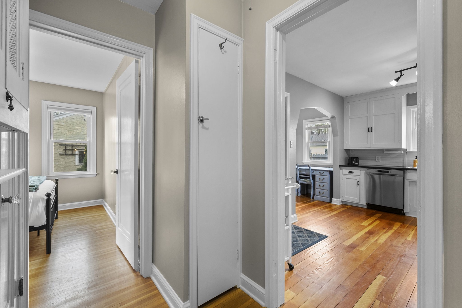 Step into a bright hallway connecting your cozy bedroom and fully-equipped kitchen, where gleaming hardwood floors and natural light create a welcoming flow throughout your home away from home.