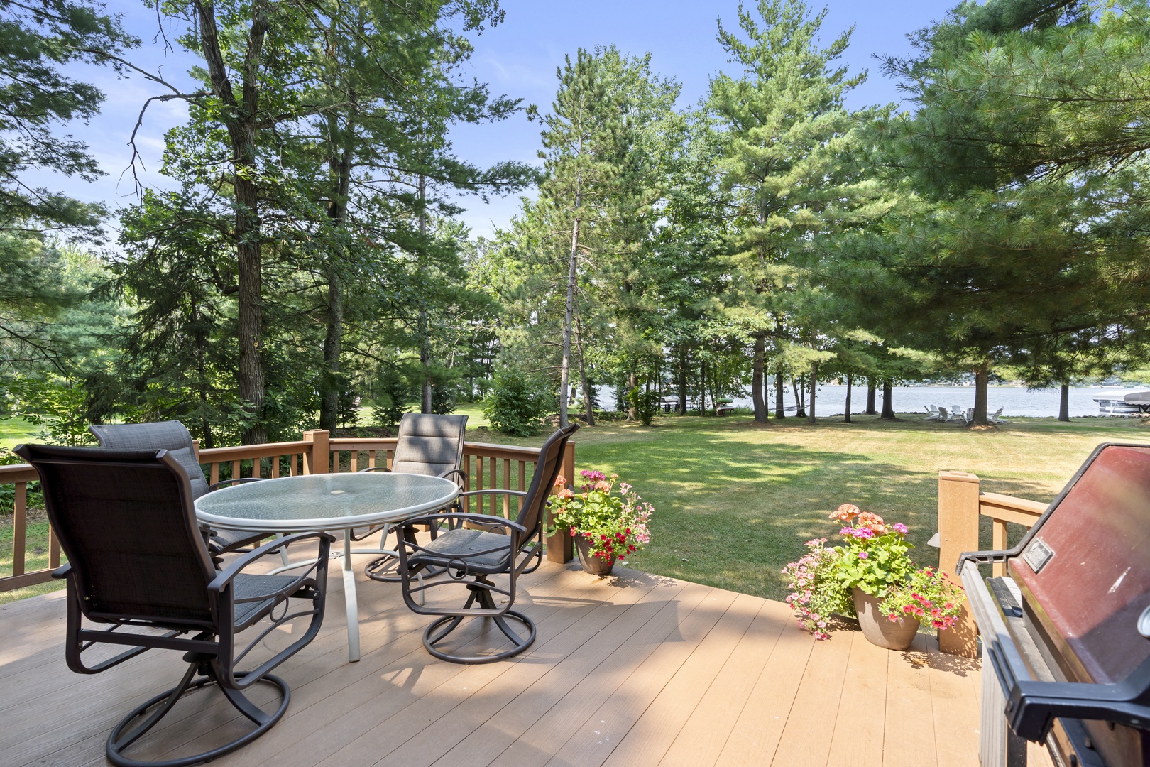Expansive deck overlooking a peaceful lakefront with trees framing the water—your perfect spot for morning coffee or evening grills with a view.