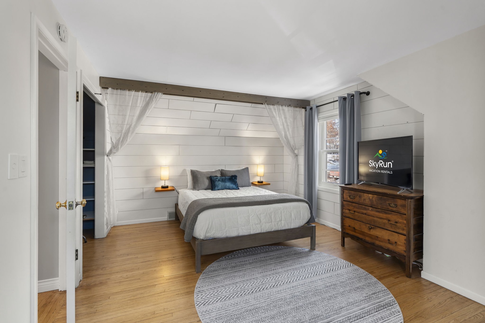 Unwind in this serene bedroom featuring a queen bed with flowing curtains and warm wood accents for your perfect retreat.