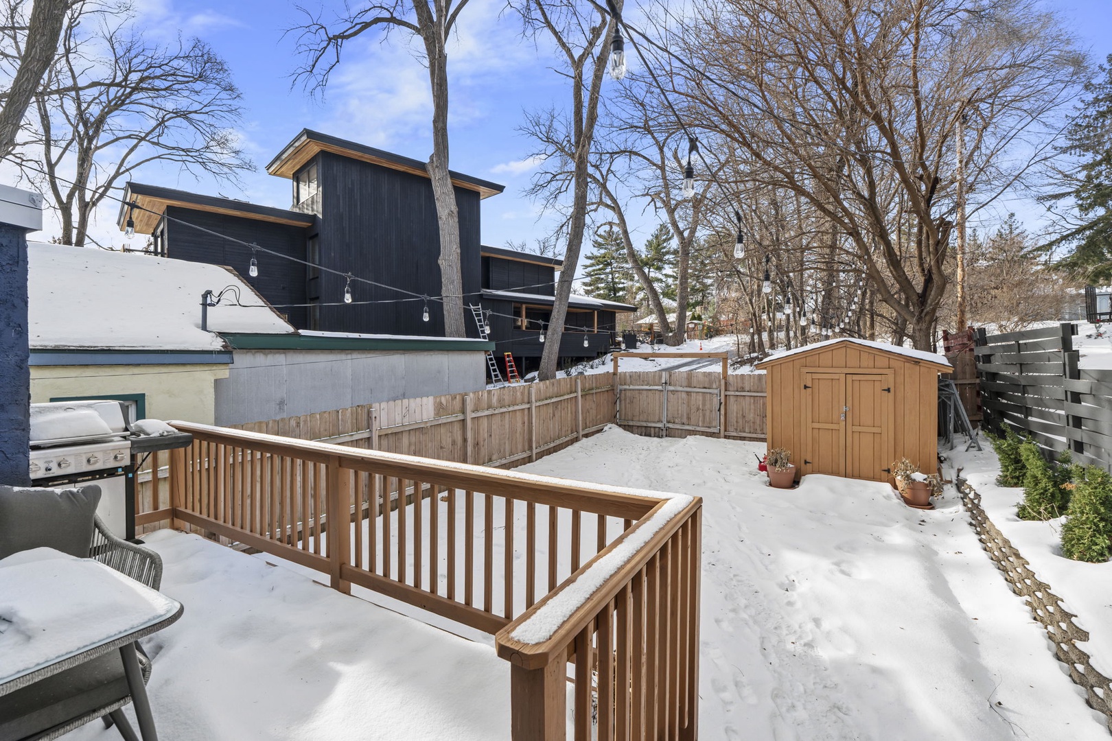 Snow-covered deck and backyard provide peaceful winter setting with modern property architecture visible in the surrounding neighborhood.