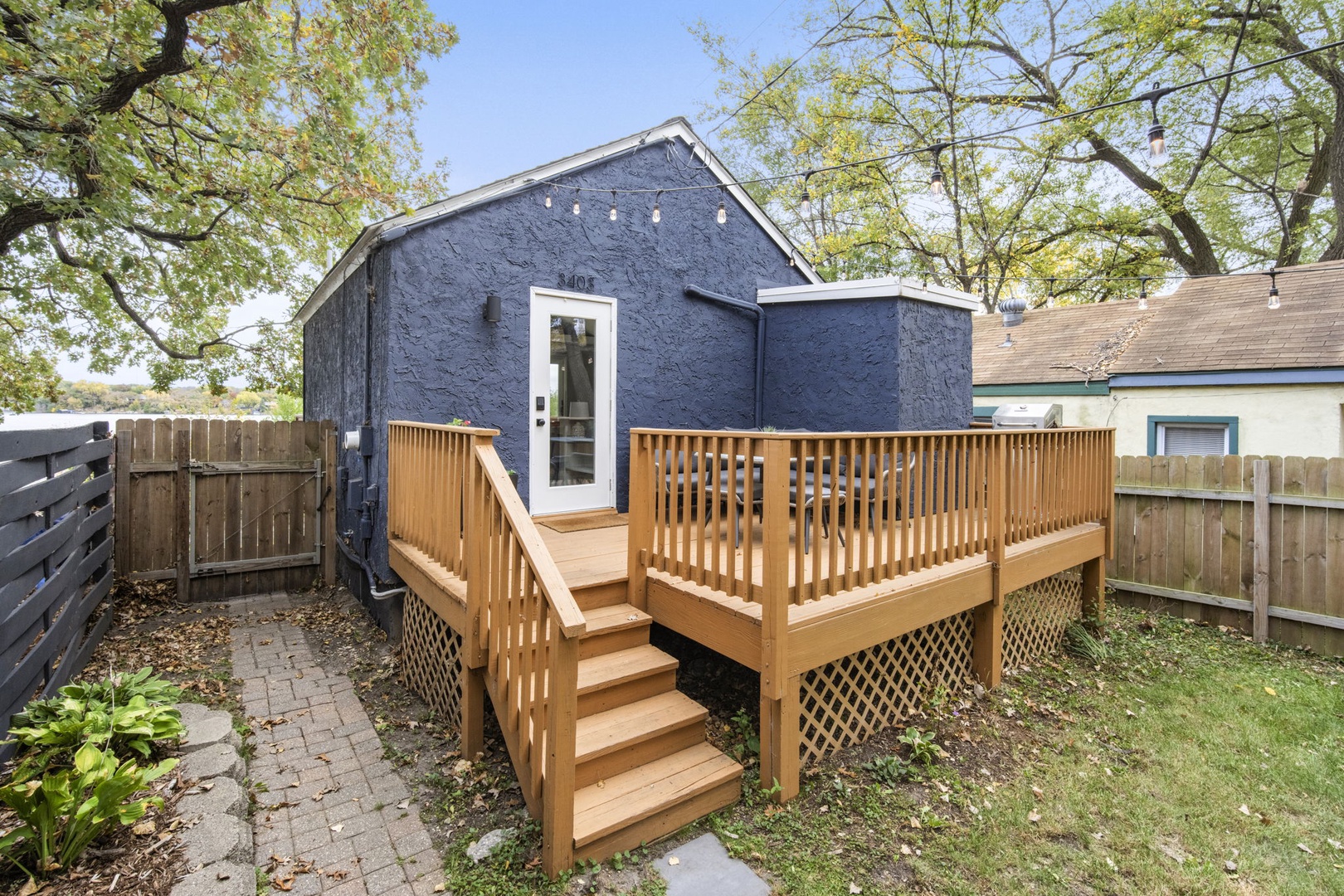 Charming standalone cottage nestled in a tree-lined backyard, featuring a spacious wooden deck for morning coffee or evening relaxation beneath nature's canopy.