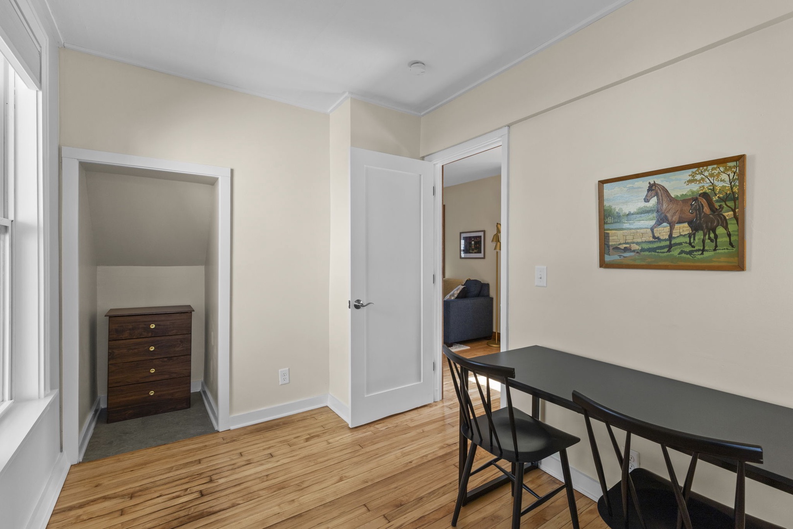 Private office/flex room with hardwood floors, a spacious desk area, dresser storage, and closet nook — perfect for work trips or longer stays.