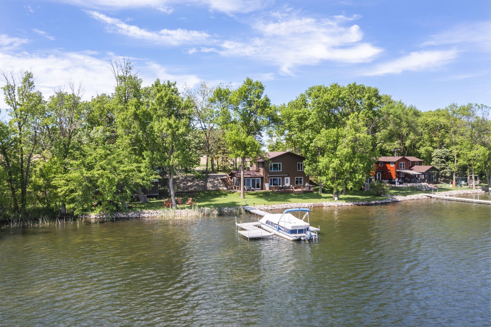 Waterfront property nestled among mature trees with private dock and boat access on a peaceful lake.