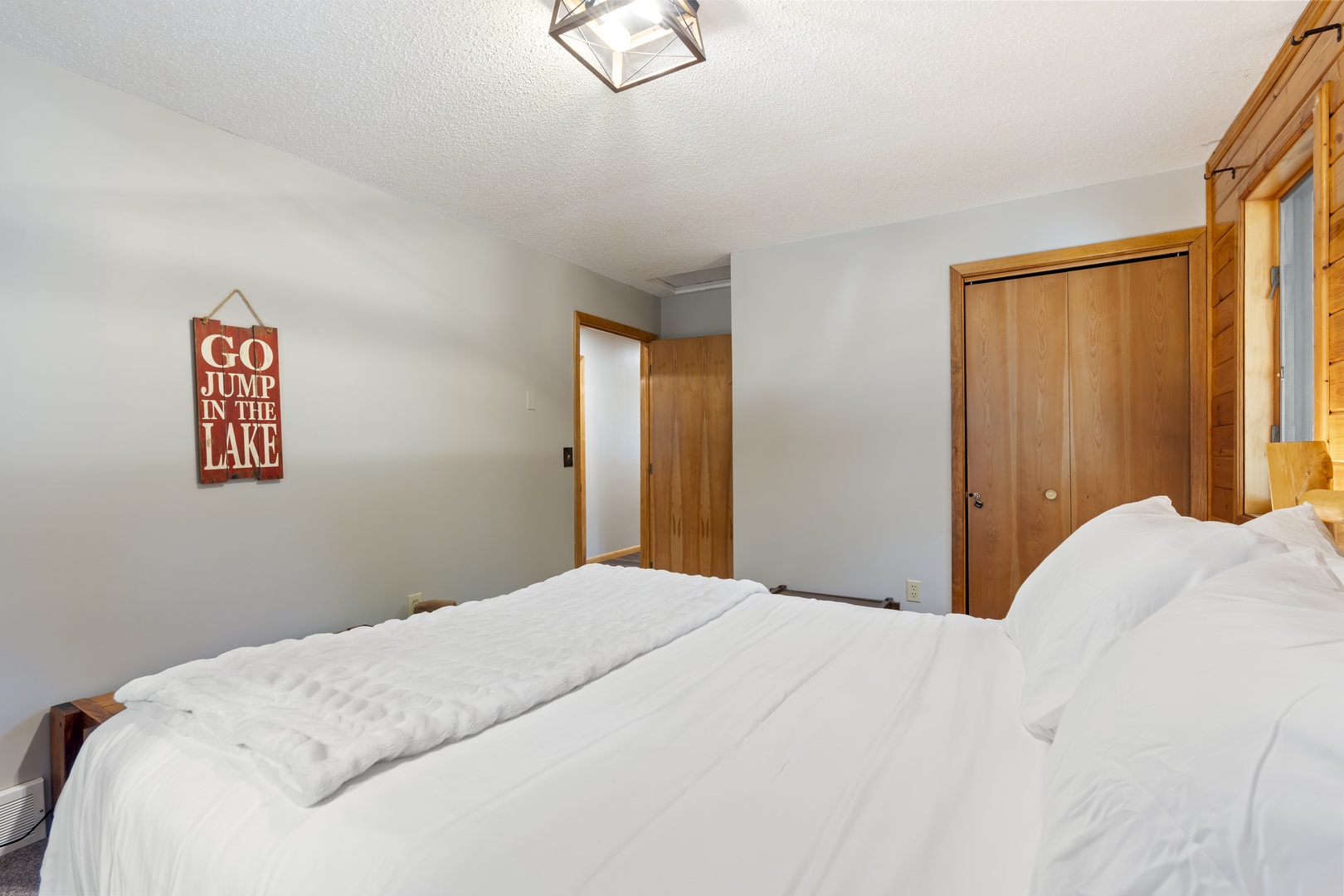 Sink into crisp white linens in your bright lakeside bedroom, with warm wood accents and charming cabin touches inviting you to unwind completely.