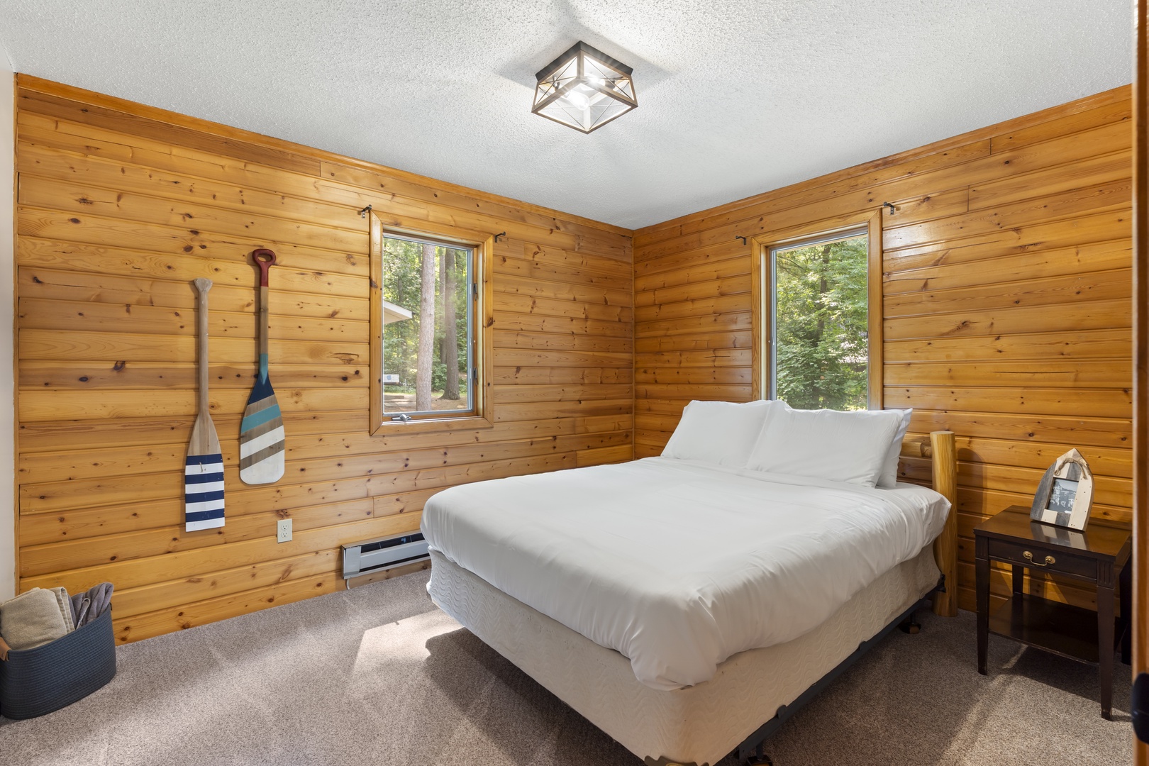 Wake up surrounded by warm wood walls and natural light filtering through windows framing forest views. Your cozy cabin bedroom invites peaceful mornings.