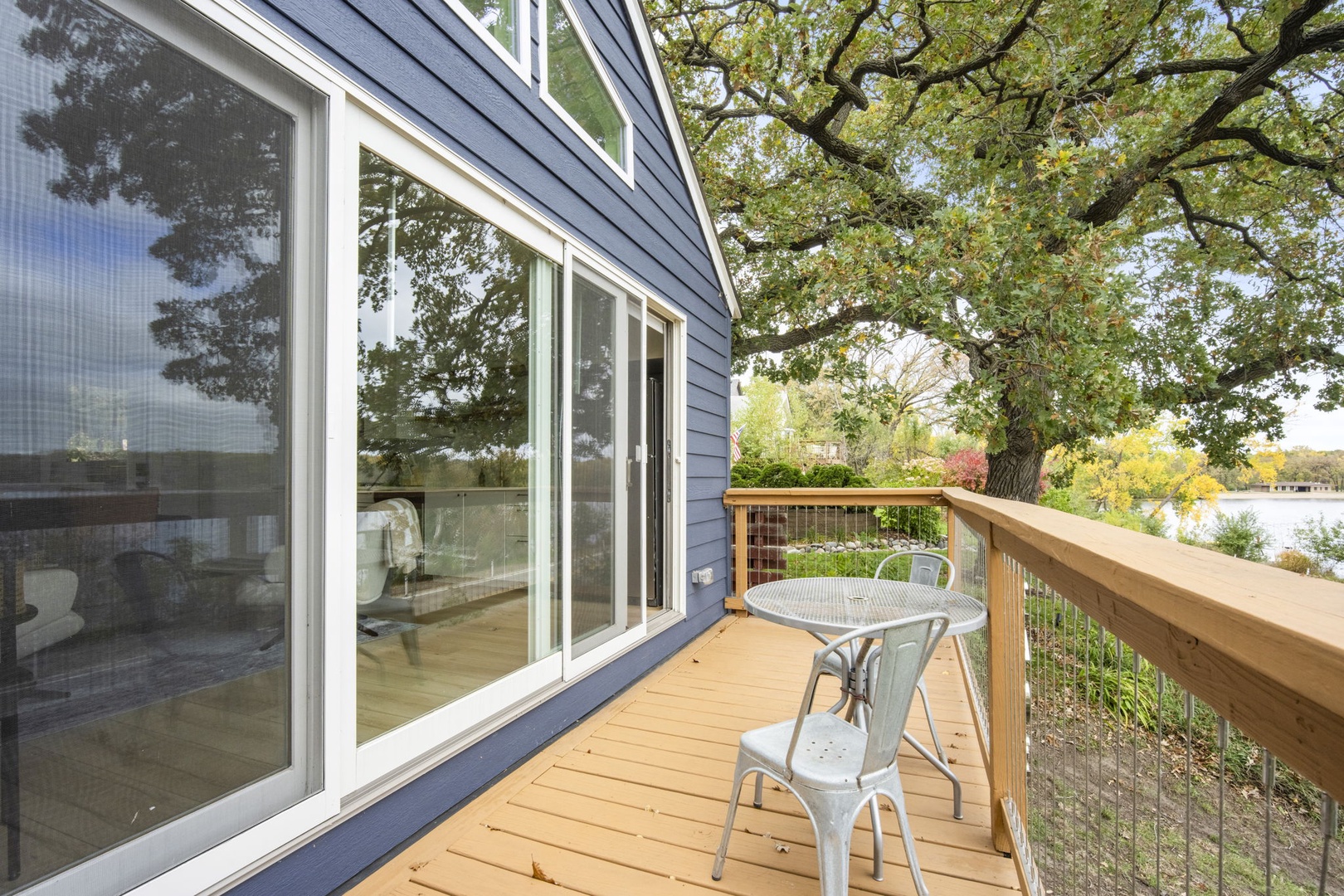 Step outside onto your private deck and breathe in the fresh air beneath towering trees. Your morning coffee or evening wind-down awaits at this peaceful lakeside retreat, where nature meets comfort.