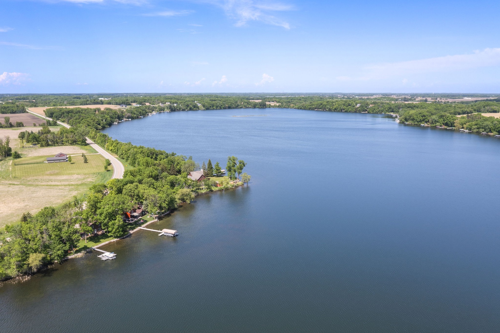 Aerial view of a serene lakefront property nestled among lush greenery, with private docks and expansive water access in a peaceful rural setting.