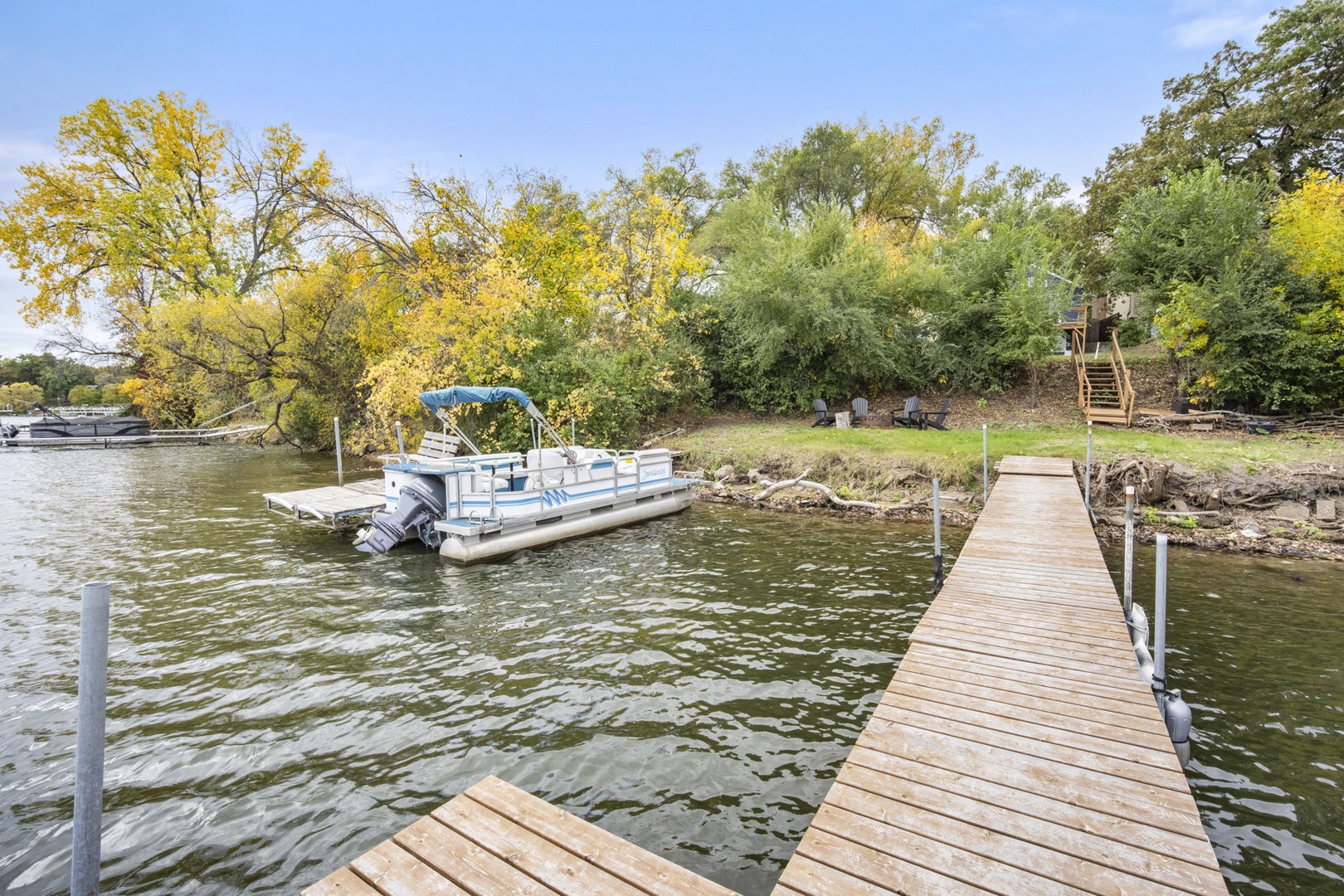 A private dock extends over calm lake waters. Golden autumn foliage frames the peaceful waterfront setting.