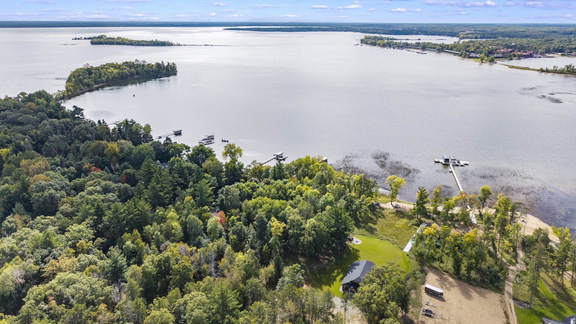 Aerial view of a waterfront property nestled among lush greenery on a tranquil lake with private dock access and peaceful surroundings.