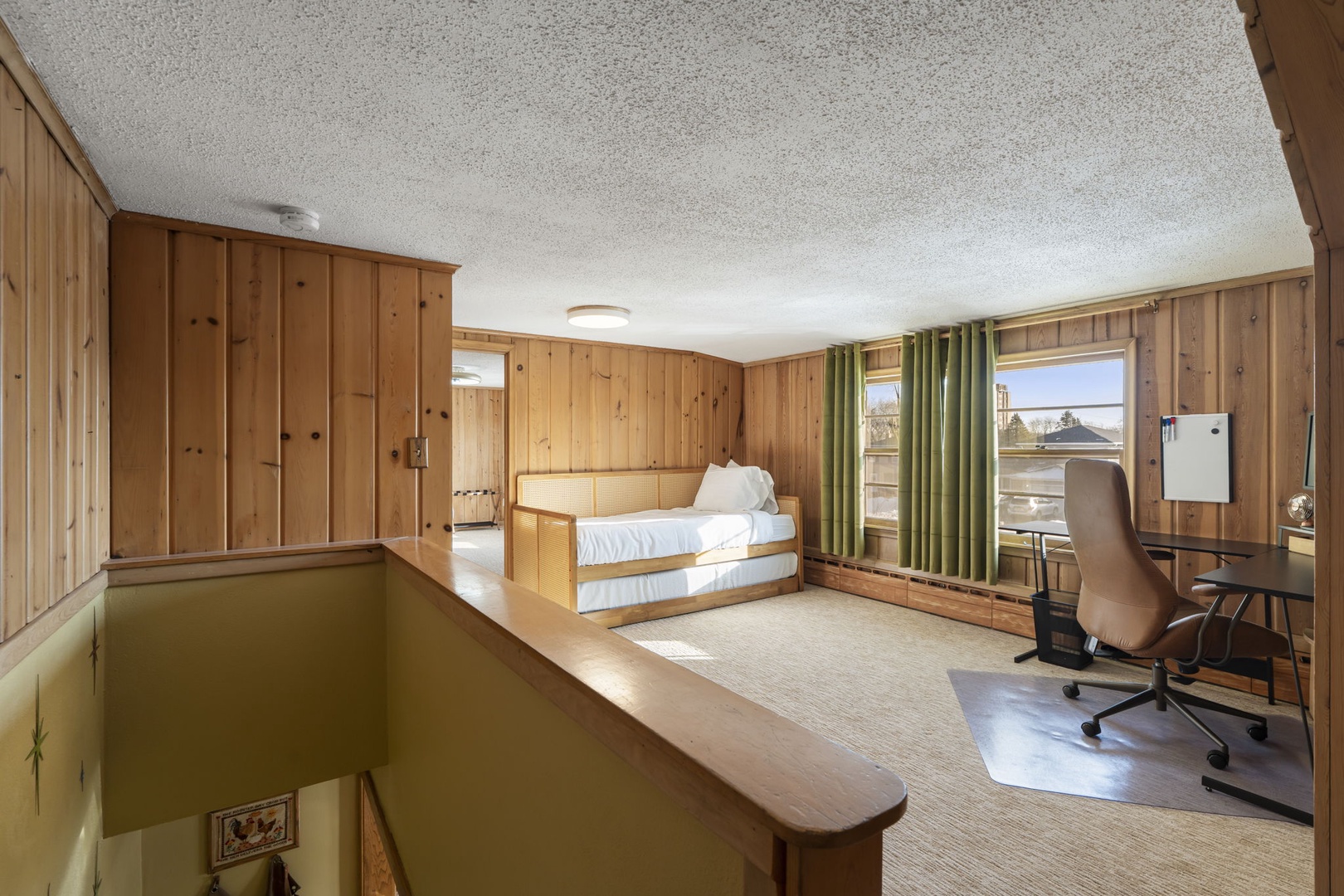The open sleeping loft features warm wood paneling, a cozy trundle bed that can be converted into a king size bed and a workspace with ergonomic chair.