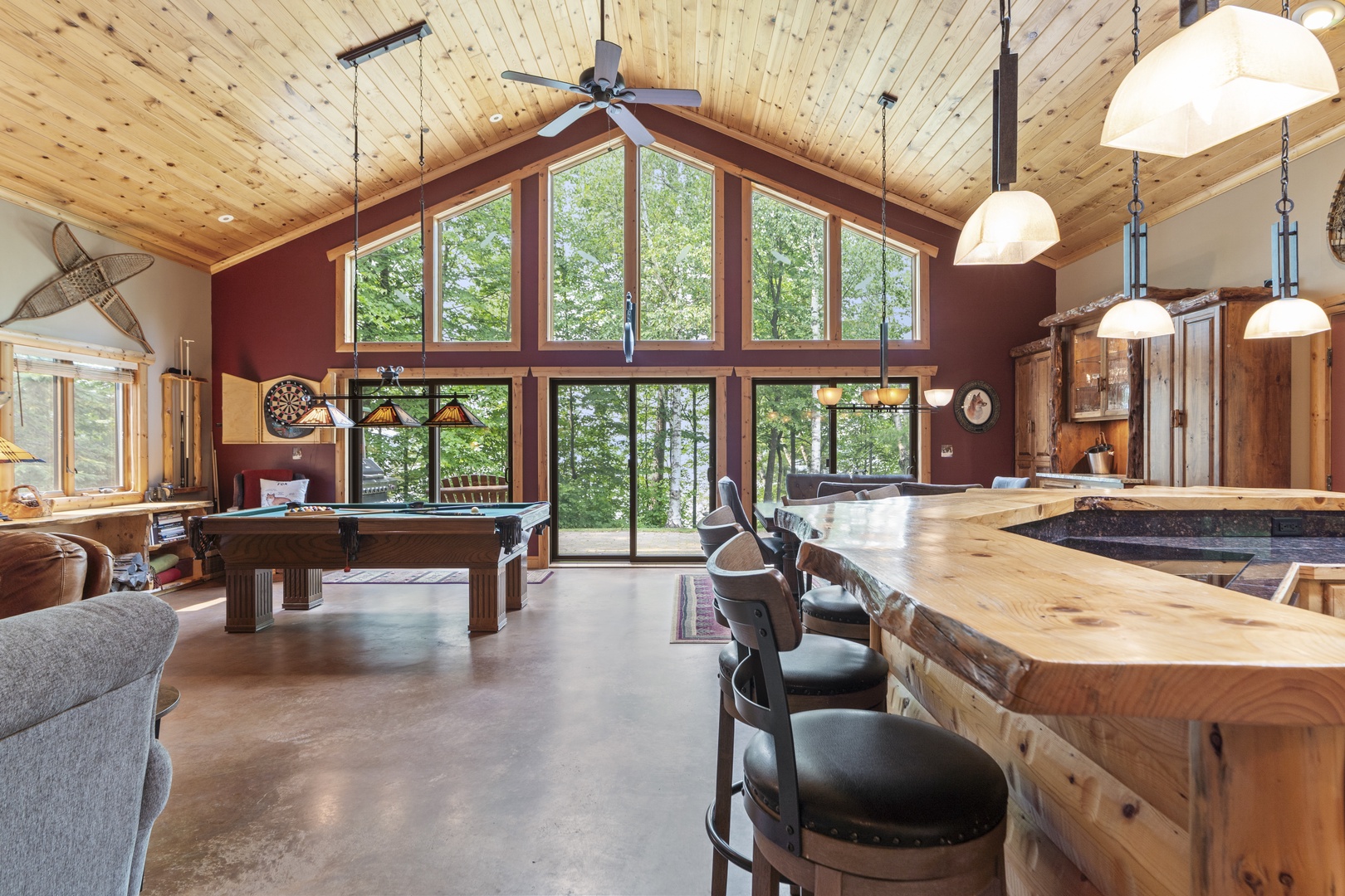Open-concept retreat with soaring windows framing peaceful forest views. Gather around the handcrafted wood bar, play billiards, or soak in natural light from floor-to-ceiling glass.