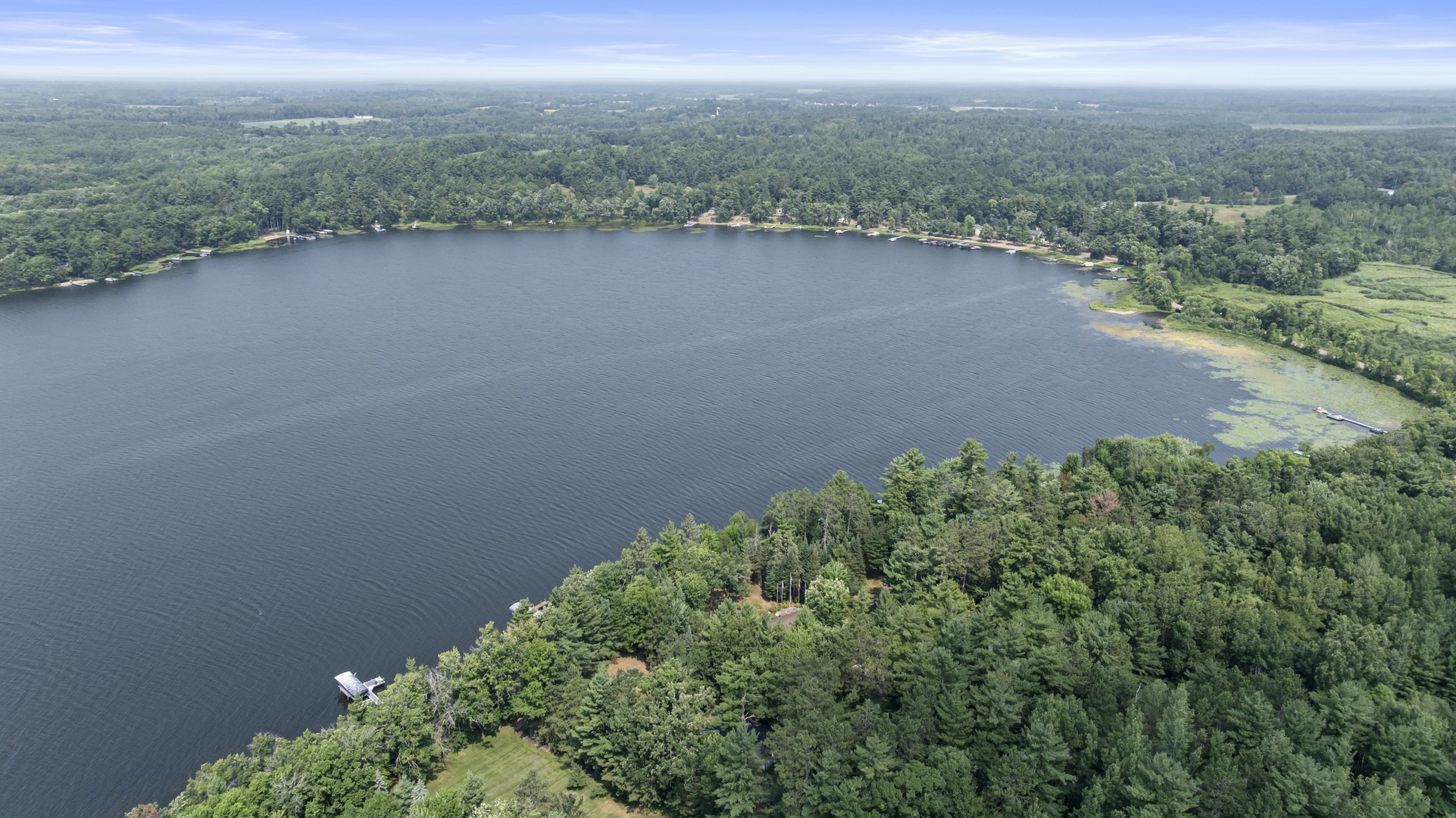 An aerial view showcasing the property's stunning lakefront setting, surrounded by lush forests and tranquil water.