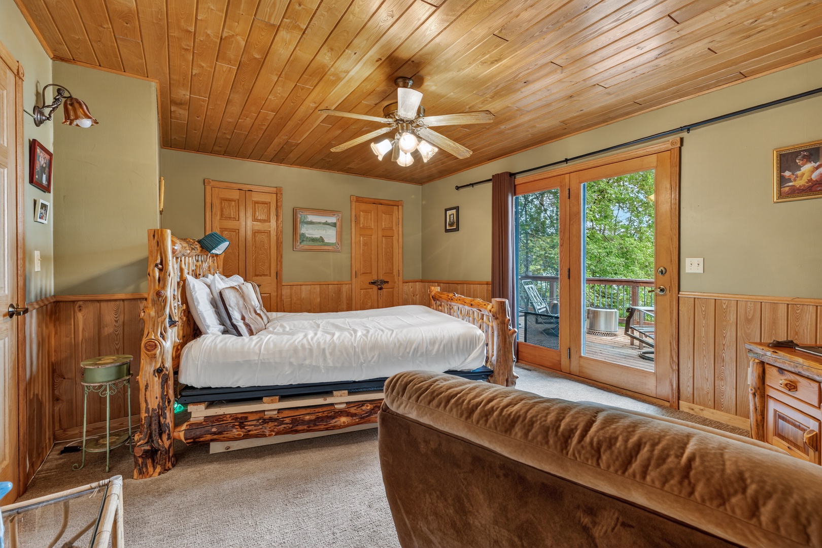 Warm wood paneling and a stunning rustic bed frame welcome you to your peaceful retreat, where glass doors open to your private balcony and forest views beyond.