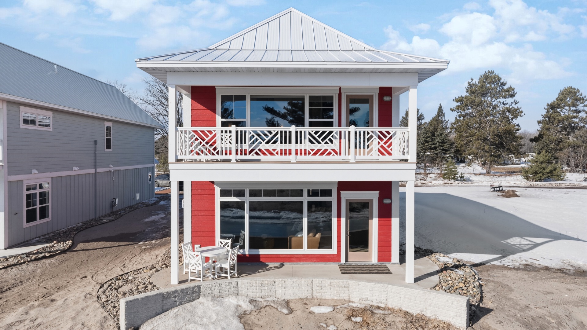 Red house back facade with covered porch balcony and metal roof