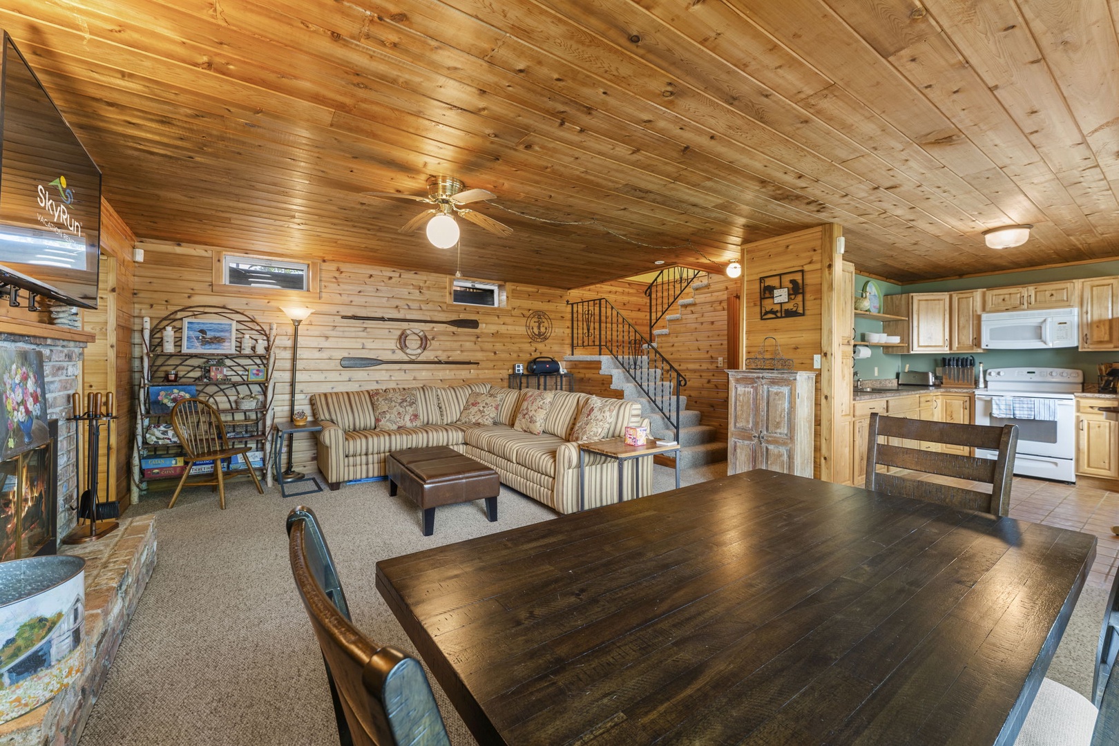 Step into your cozy cabin retreat with warm pine walls, vaulted ceilings, and an open layout perfect for gathering. Relax on the comfy sofa, share meals at the dining table, and enjoy the rustic charm throughout.
