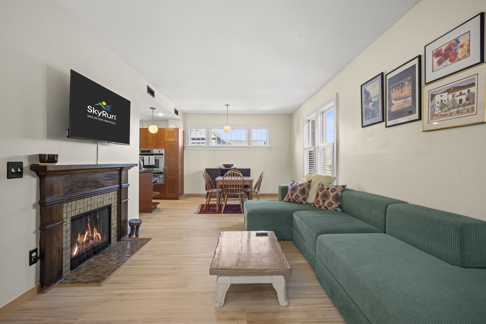 Sink into the plush green sofa and feel right at home in this bright, open living space. Enjoy cozy evenings by the fireplace or gather at the dining table for memorable meals together.