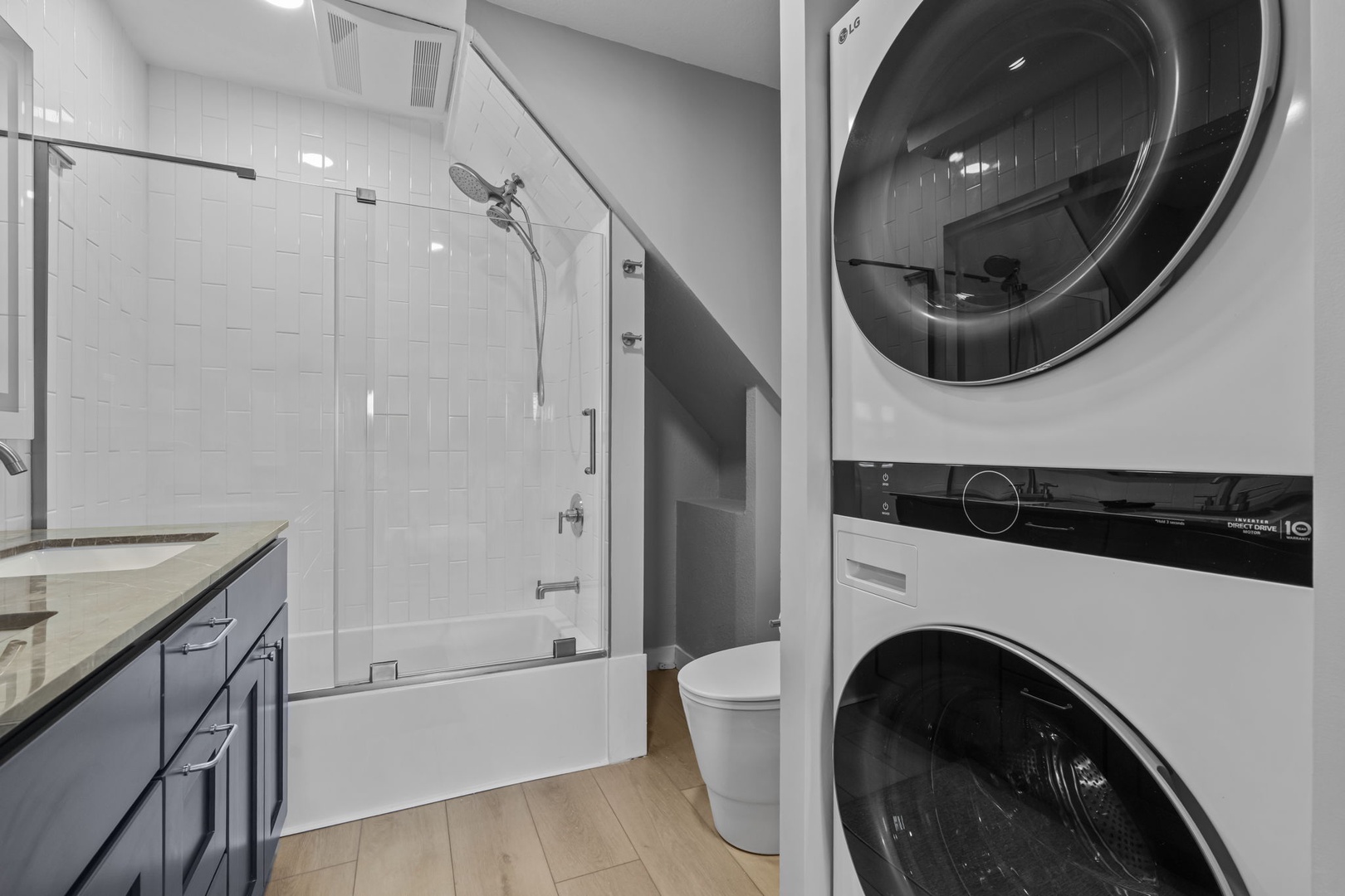 Your private bathroom features a sleek glass shower, modern vanity, and convenient in-unit washer and dryer for ultimate comfort during your stay.