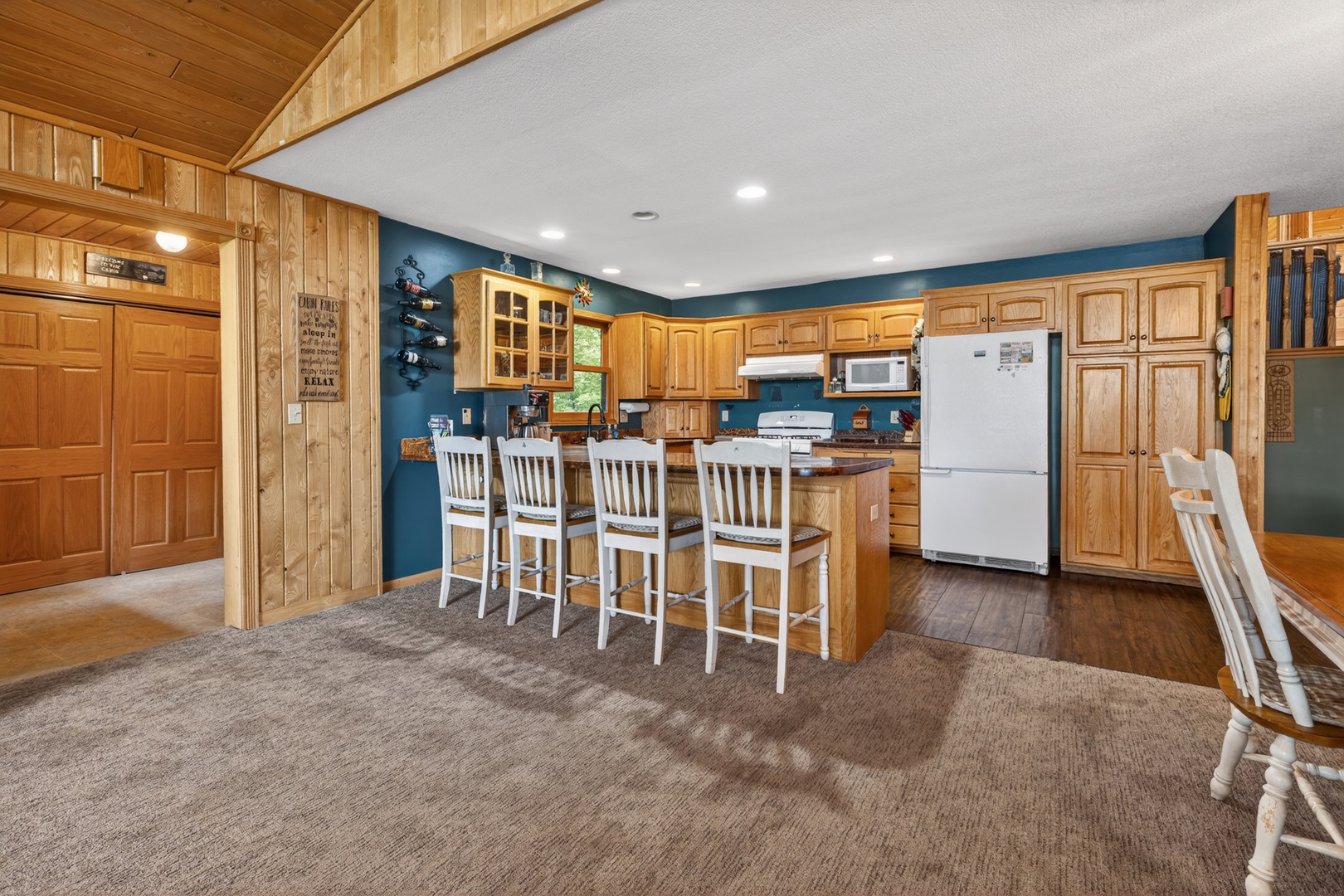 Gather around the inviting kitchen island with your group, where rustic wood cabinetry meets modern amenities. The open layout and charming vaulted ceilings create a warm space for meal prep and conversation.