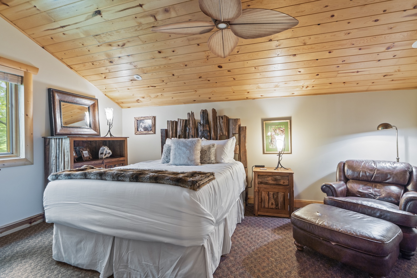 Sink into soft white linens beneath a beautifully vaulted wood ceiling. Your rustic headboard and cozy reading chair create the perfect mountain retreat ambiance.
