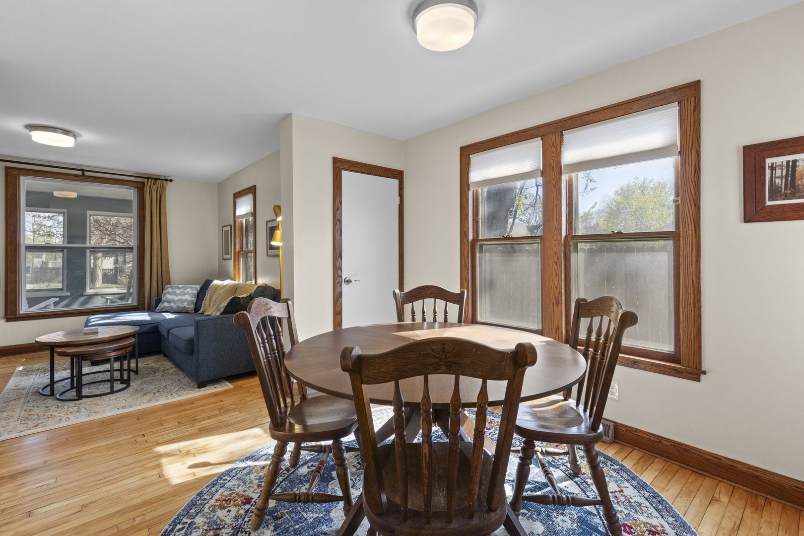 Classic dining room with round wood table, seating for four, and original hardwood floors — opens to the living room for easy entertaining.