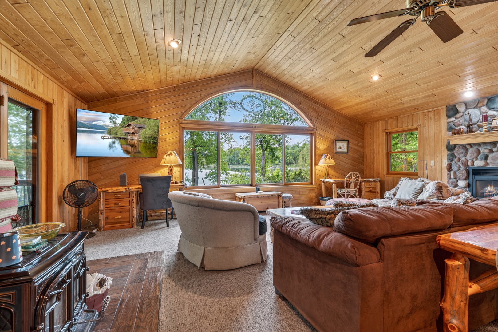 Sink into plush sofas and gaze through stunning arched windows at your private lake view—your perfect escape blends rustic warmth with serene waterfront tranquility.