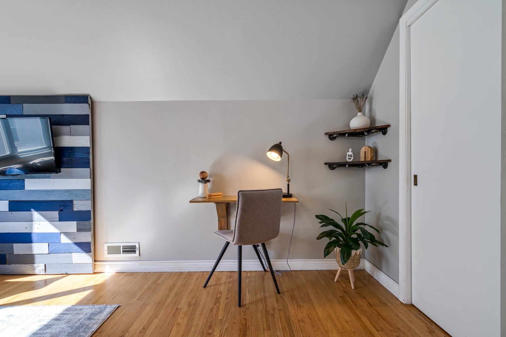 Your perfect work-from-home sanctuary features a sleek desk, comfortable chair, and floating shelves in a bright, naturally lit space.