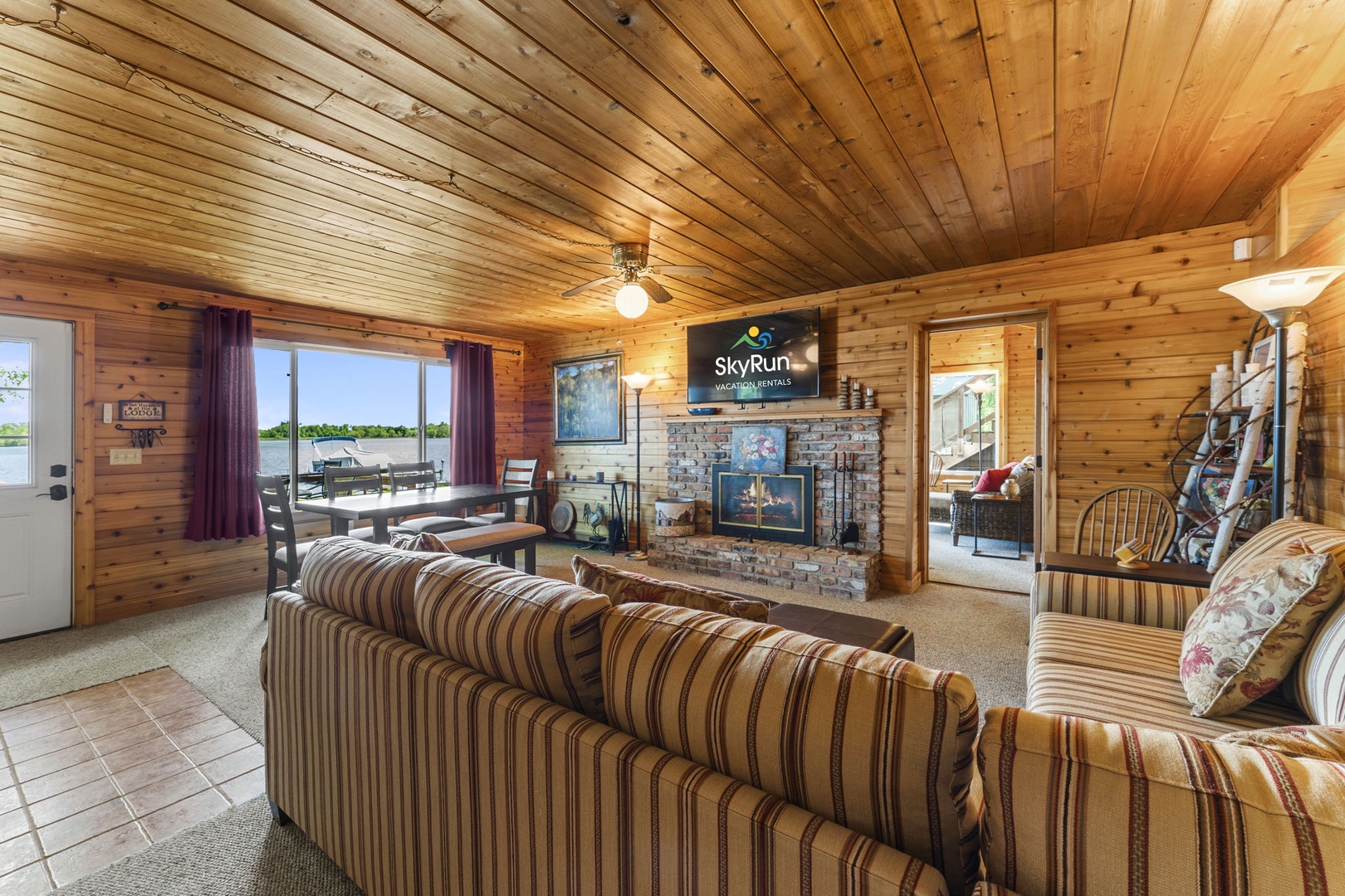 Sink into plush seating and enjoy cozy evenings by the stone fireplace in this inviting living area with stunning lake views just steps away.