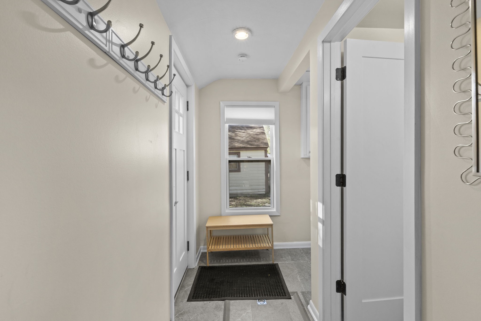 Convenient back mudroom entry with wall-mounted coat hooks, bench with shoe storage, and tile floor — easy in and out for busy days.