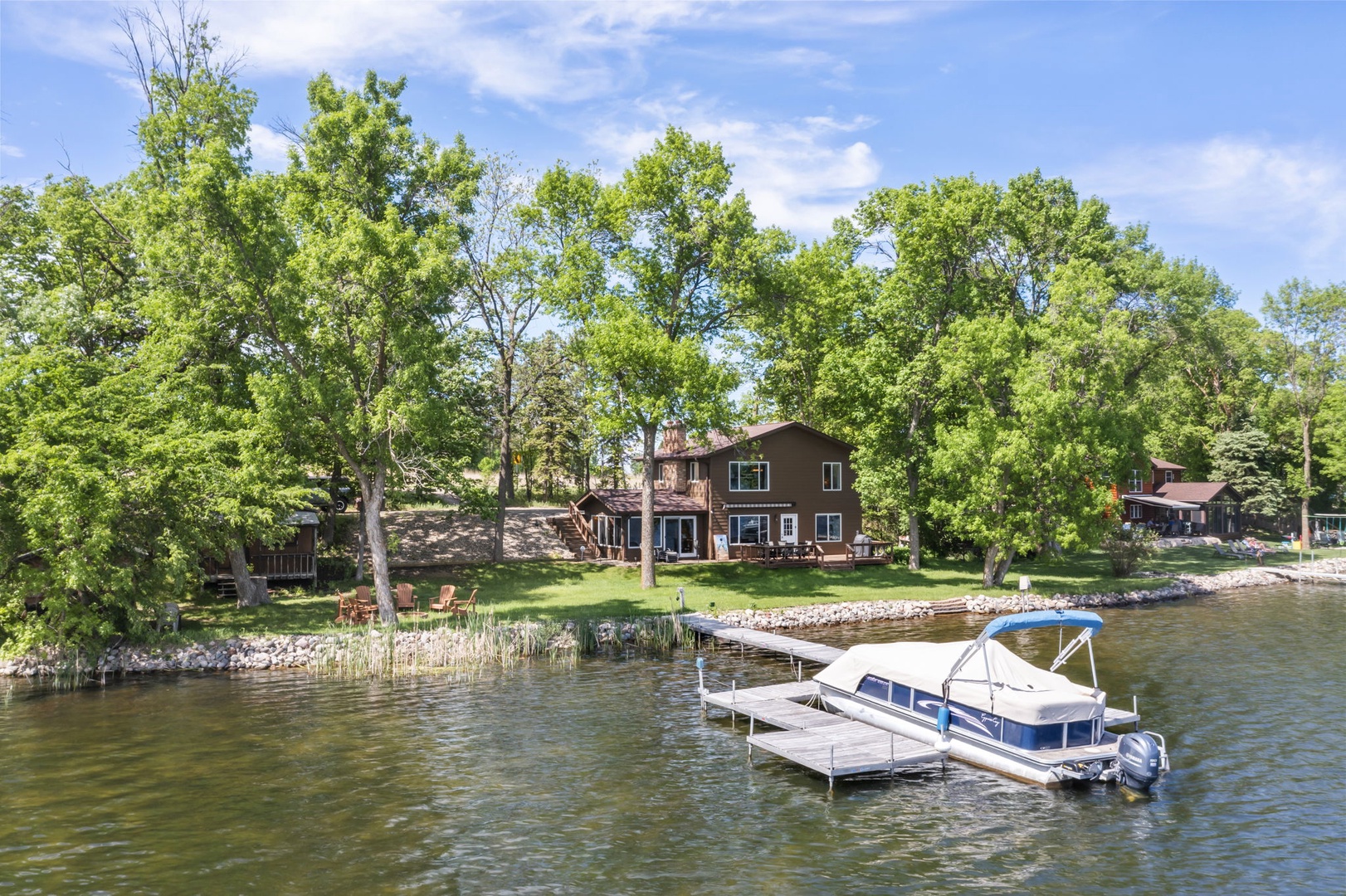 Waterfront property nestled along a peaceful lake, surrounded by mature trees and featuring a private dock ready for summer fun.