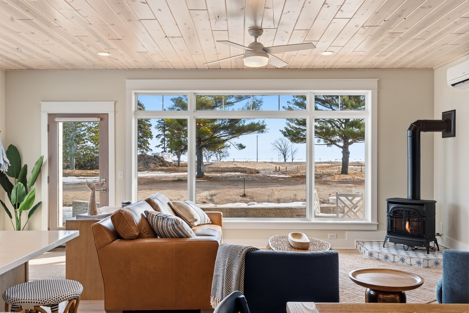 Bright living room with panoramic windows leather sofa and wood stove